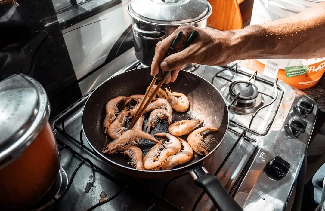 Person efficiently using oven, stovetop, and microwave simultaneously for meal prep in a modern kitchen.