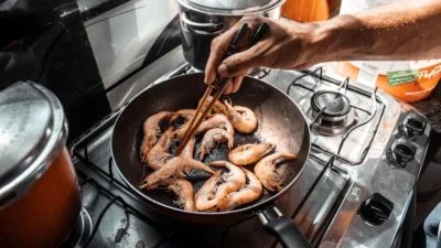 Person efficiently using oven, stovetop, and microwave simultaneously for meal prep in a modern kitchen.